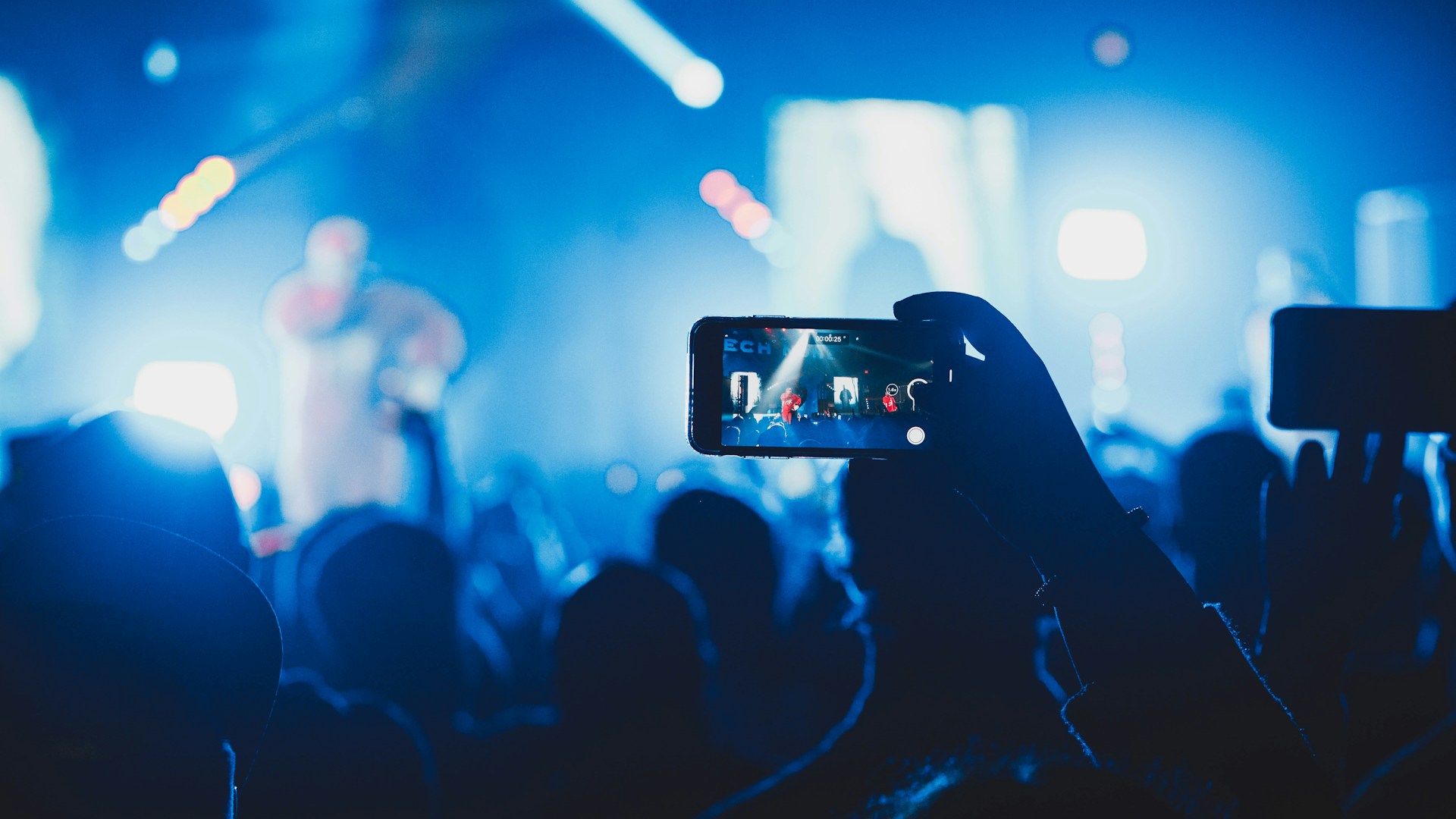 Fans grabando a un artista con sus smartphones bajo luces azules