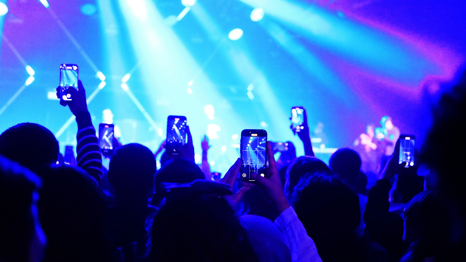 Una audiencia comparte un concierto en vivo, con teléfonos alzados frente al escenario